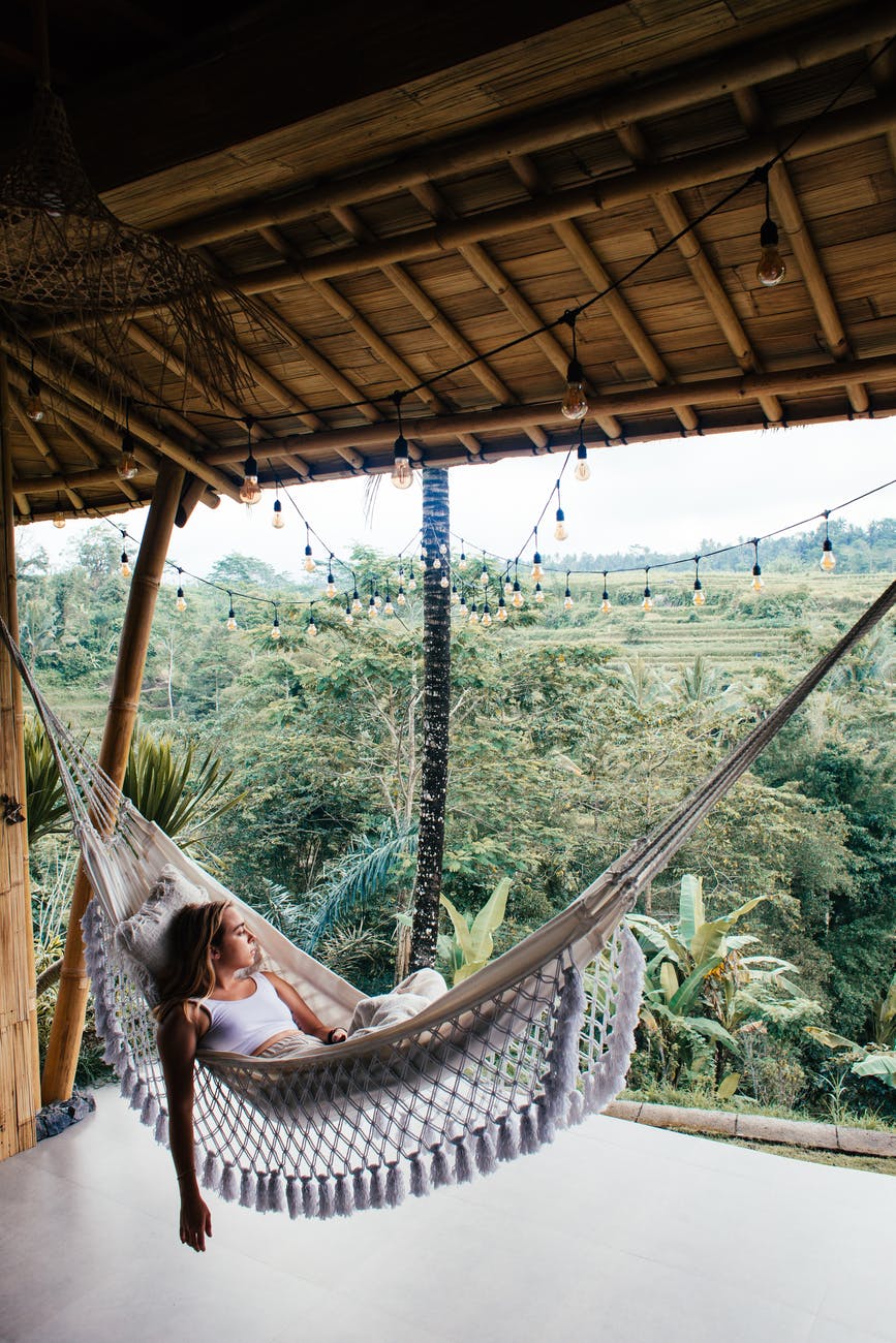 relaxed female tourist contemplating nature from hammock on terrace