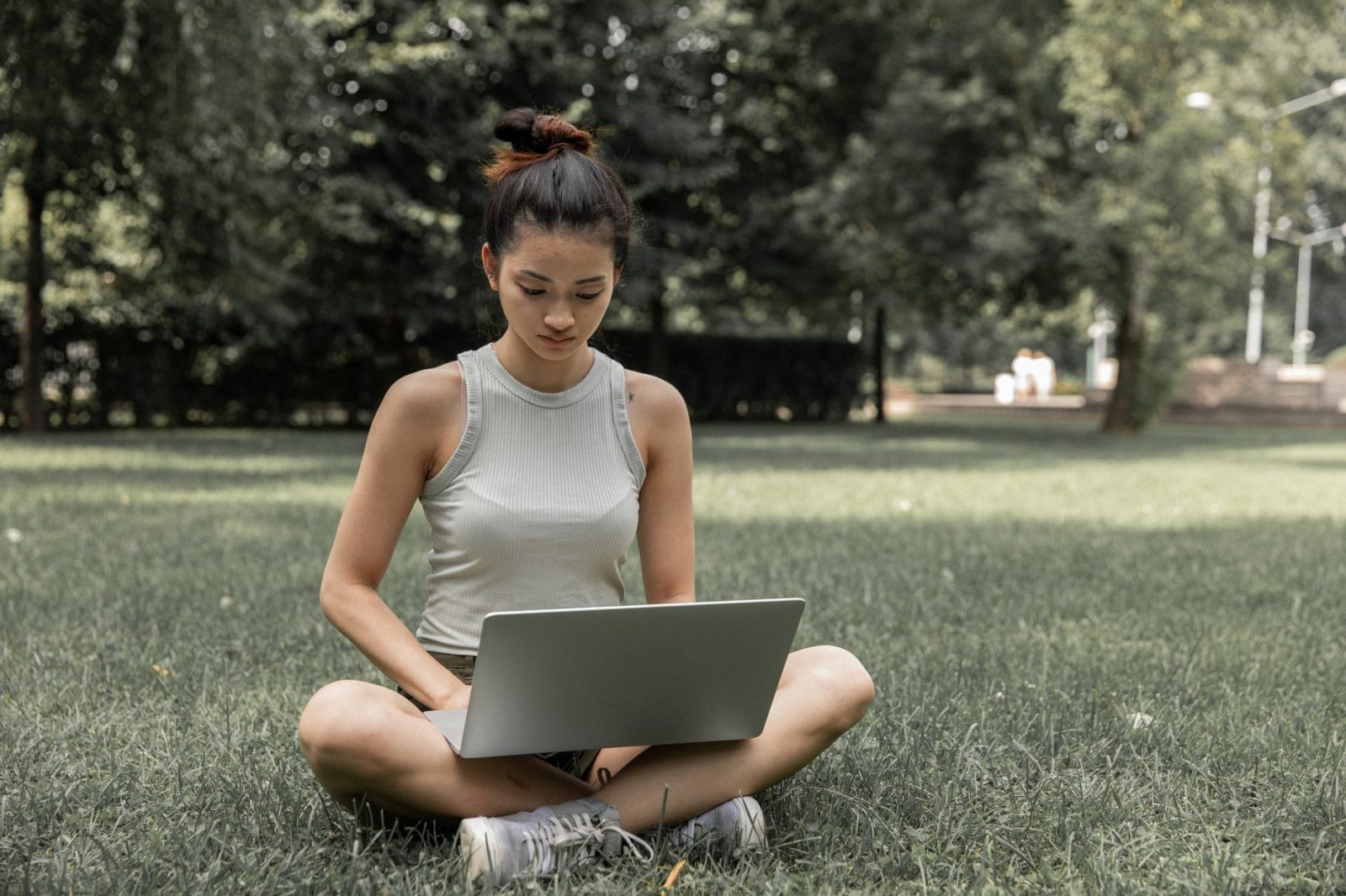 concentrated asian woman browsing laptop in park