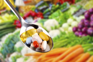 spoon with pills, dietary supplements on vegetables
