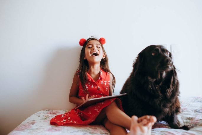 photo of girl sitting beside black dog