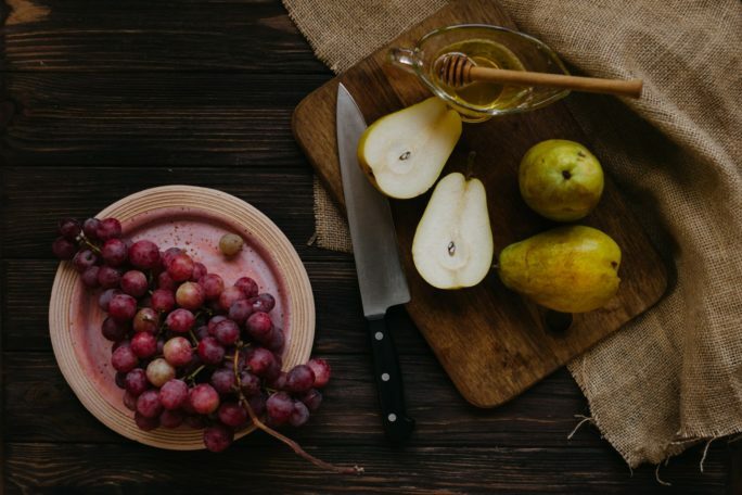 board with pears and honey near grapes