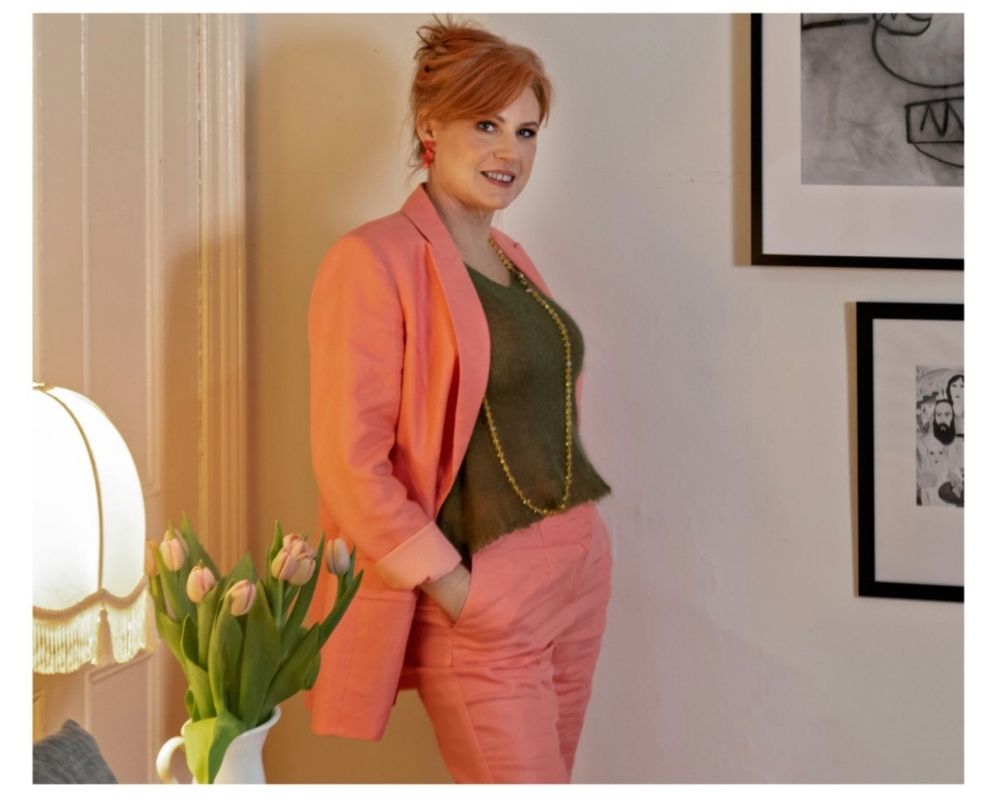 Donna Cameron wearing a coral pink suit and green top.