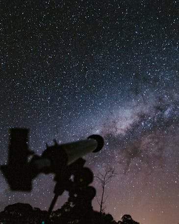 A breathtaking view of the starry night sky with a telescope silhouette capturing the beauty of the cosmos.