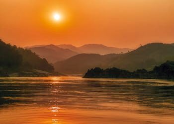 Serene sunset landscape over the Mekong River with scenic mountains in Bokeo Province, Laos.