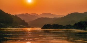 Serene sunset landscape over the Mekong River with scenic mountains in Bokeo Province, Laos.